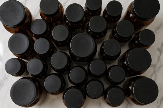 Overhead view of amber supplement bottles with black caps on a marble counter